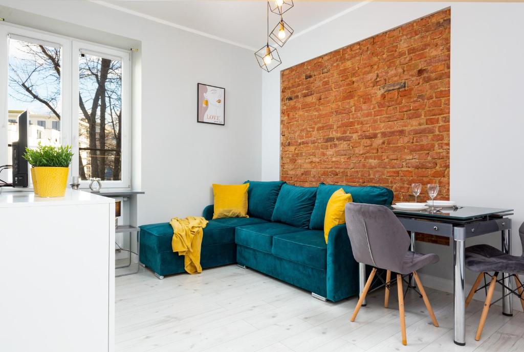 a living room with a blue couch and a brick wall at Stylish & Modern Apartments Praga in Warsaw