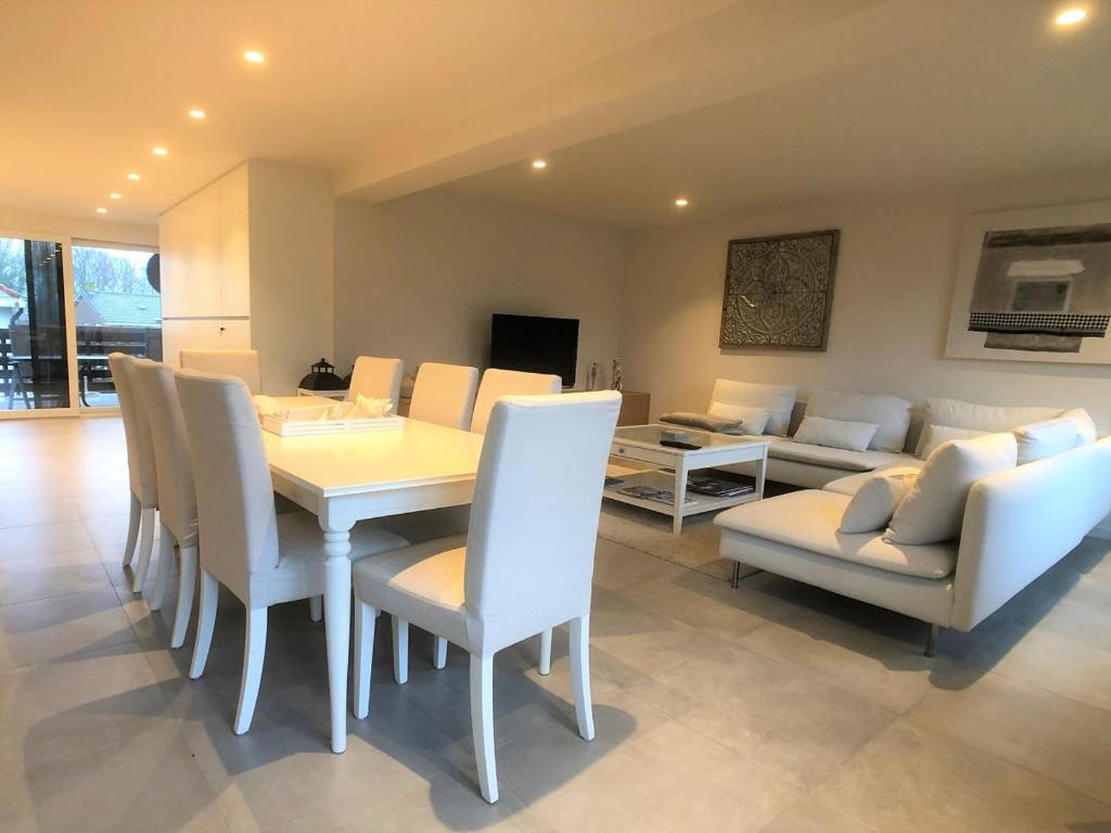 Un comedor con una mesa y sillas y un sofá. en De Tureluur, en Cadzand
