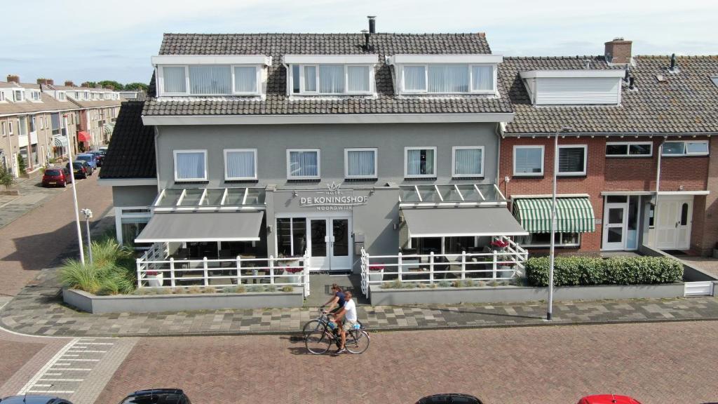 een persoon die fietst voor een gebouw bij Hotel De Koningshof in Noordwijk aan Zee