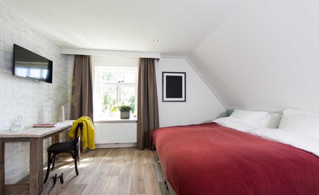 een slaapkamer met een bed, een bureau en een raam bij Vakantiewoning De Beiert in Delden