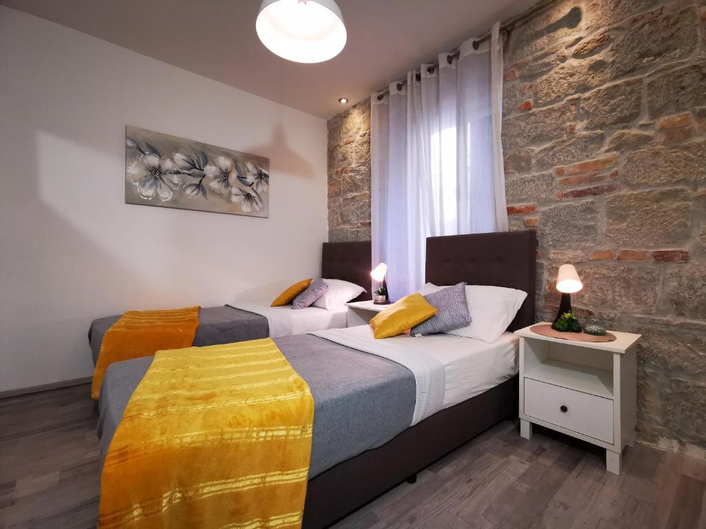 a bedroom with two beds and a stone wall at Apartment Herc in Split