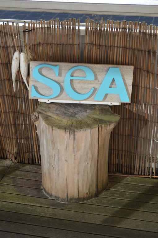 una señal que dice mar sentado en la parte superior de un tronco de árbol en Sea en Egmond aan Zee