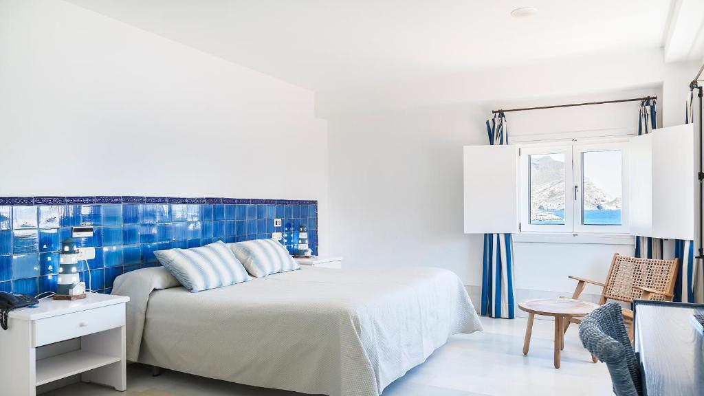a white bedroom with a bed and a chair at Doña Pakyta in San José