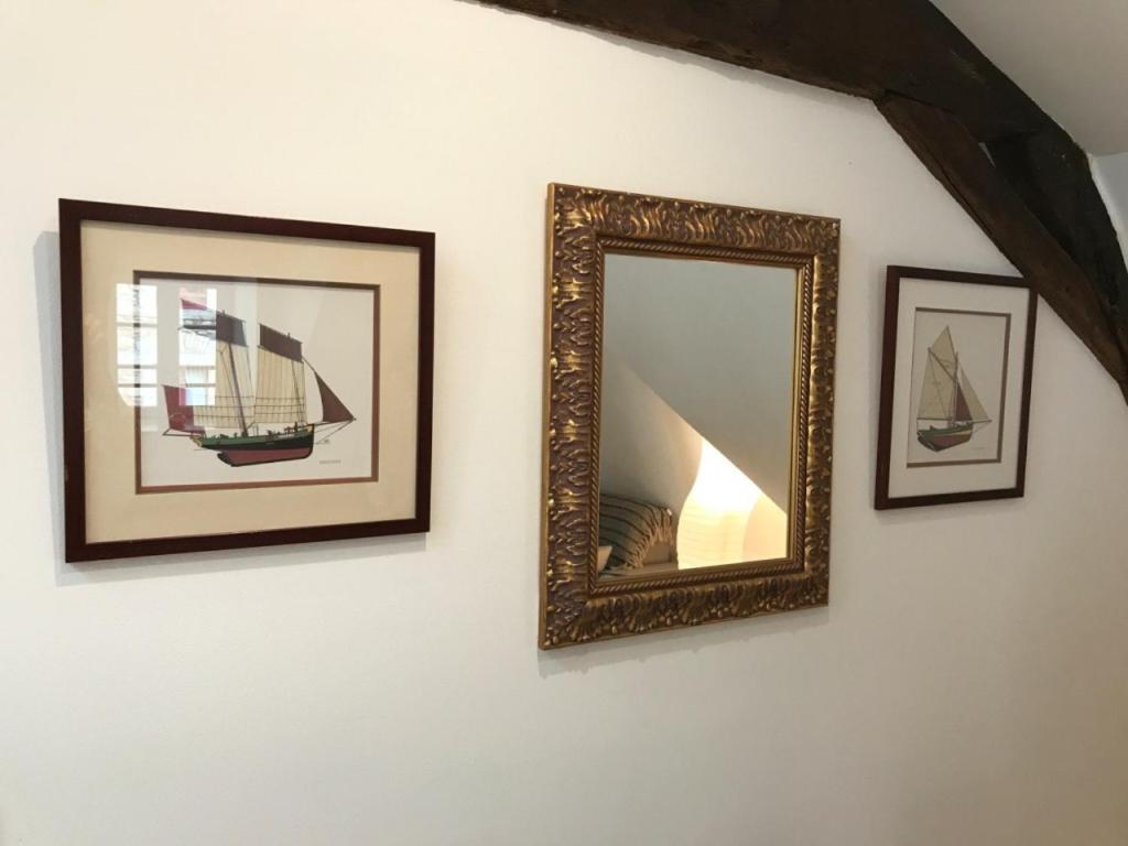 a mirror on a wall with three pictures of a boat at Appartement de charme rue du Château in Auray