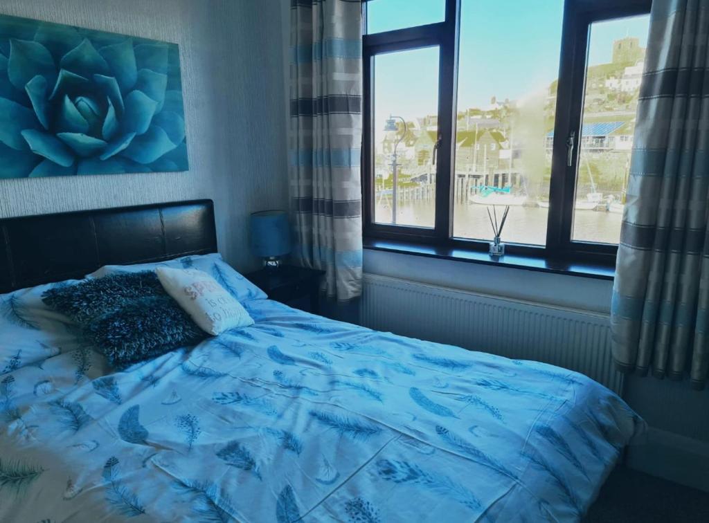 1 dormitorio con 1 cama con edredón azul y 2 ventanas en The Buck Inn, en Whitby