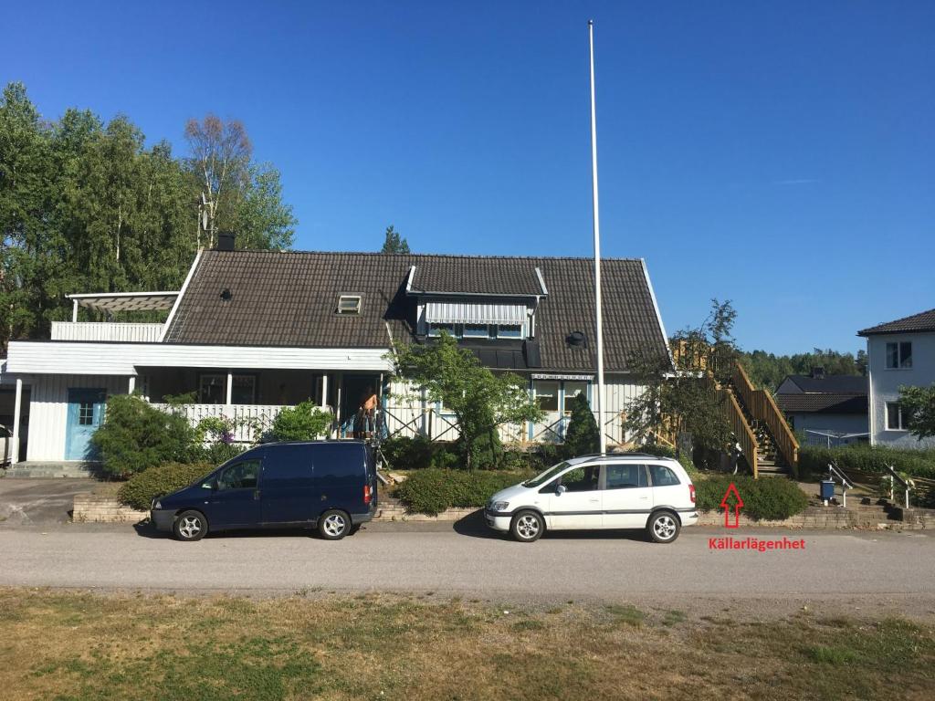 two cars parked in a parking lot in front of a house at Källarlägenhet Centrumvägen Gusum in Gusum