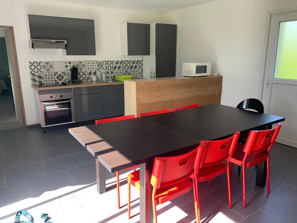 une cuisine avec une table noire et des chaises rouges dans l'établissement LE GITE COTE D OPALE, à Calais