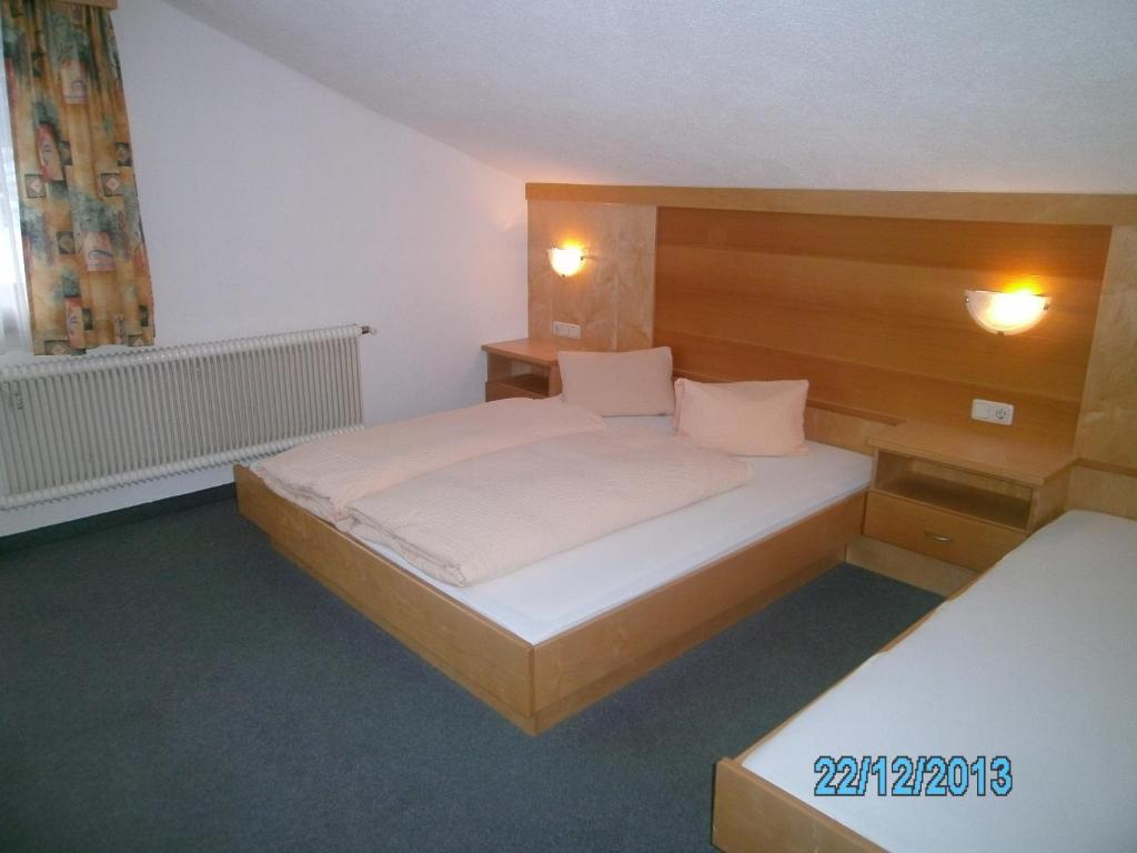 a bedroom with a bed with a wooden headboard at Gästehaus Hirschenhof in Sölden