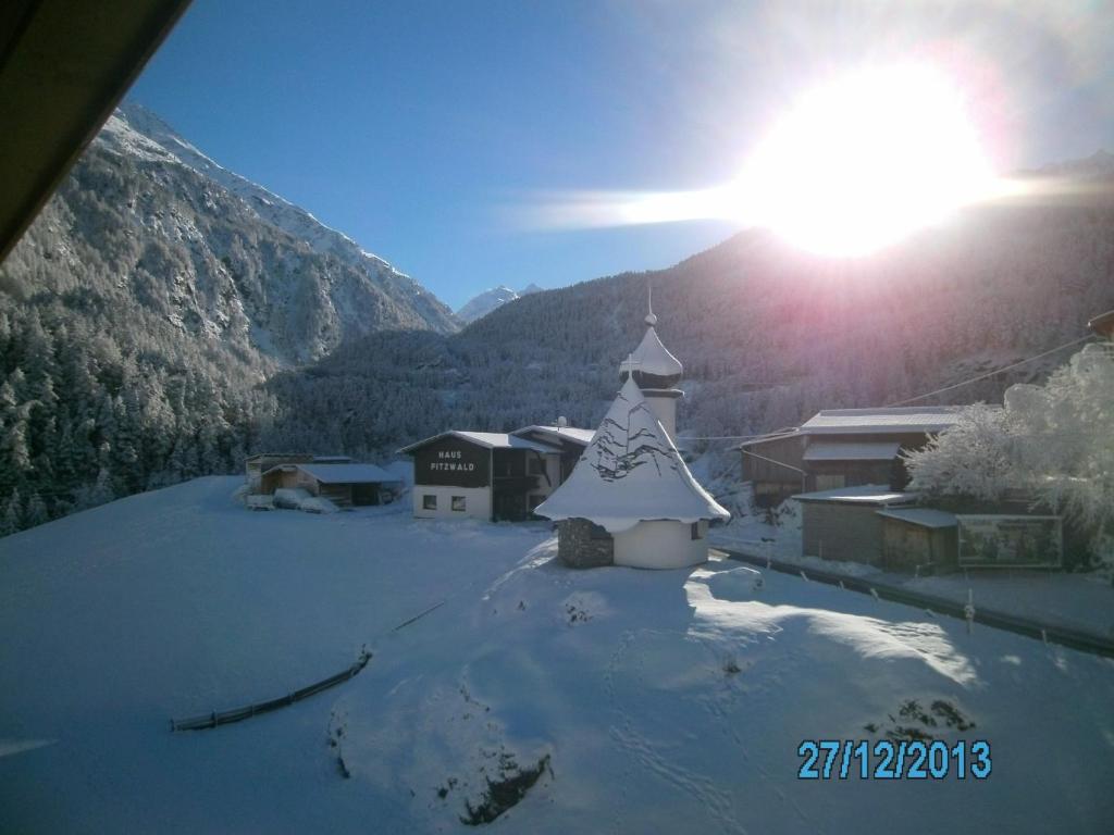 a snow covered village with a christmas tree on a mountain at Gästehaus Hirschenhof in Sölden
