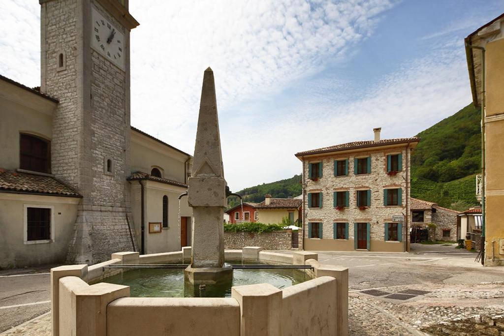 ヴァルドッビアーデネにあるLe Zitelle di Ronの時計塔と噴水のある町