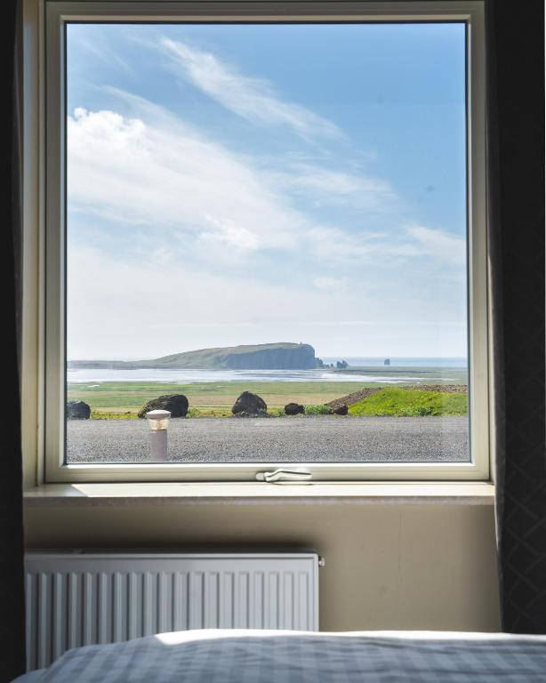 a bedroom window with a view of the ocean at Hótel Dyrhólaey in Vík
