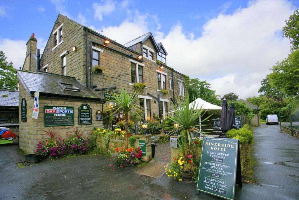 Ilkley Riverside Hotel في إلكلي: مبنى من الطوب وامامه لافته