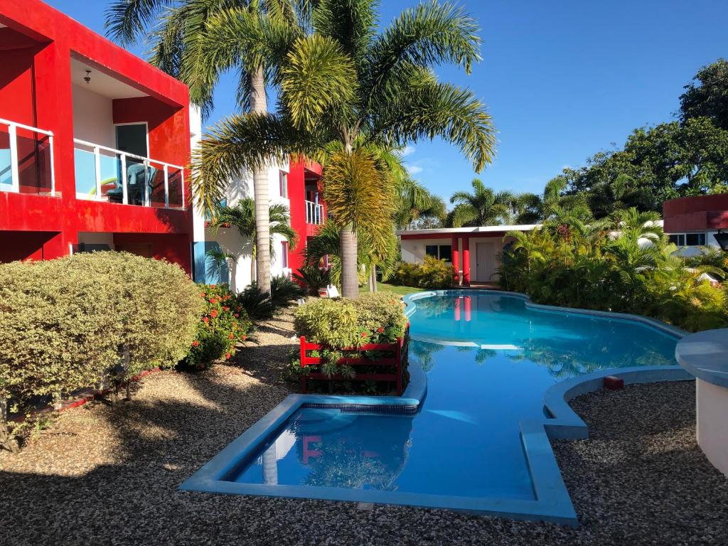 a swimming pool in front of a house with a red building at Agua Del Caribe in Sosúa