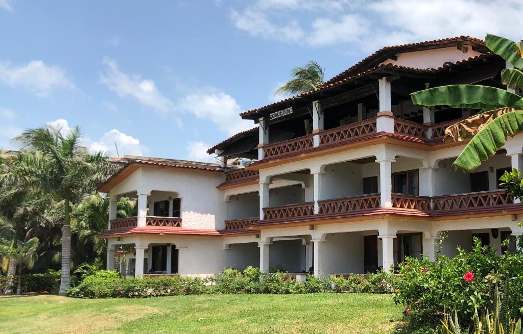 a large building with balconies on top of a yard at Hotel Arcoiris in Puerto Escondido