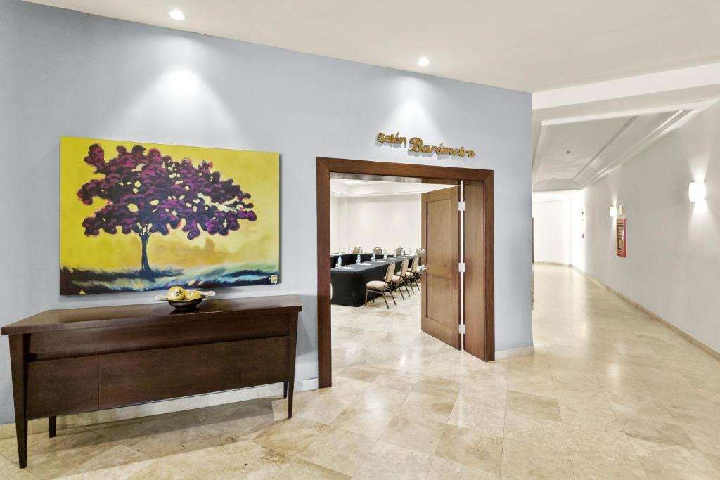 a hallway with a door and a tree painting on the wall at Hotel Aeropuerto Los Cabos in San José del Cabo