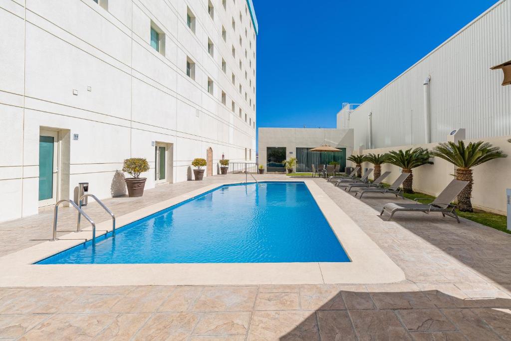 a swimming pool in front of a building at Hotel Aeropuerto Los Cabos in San José del Cabo