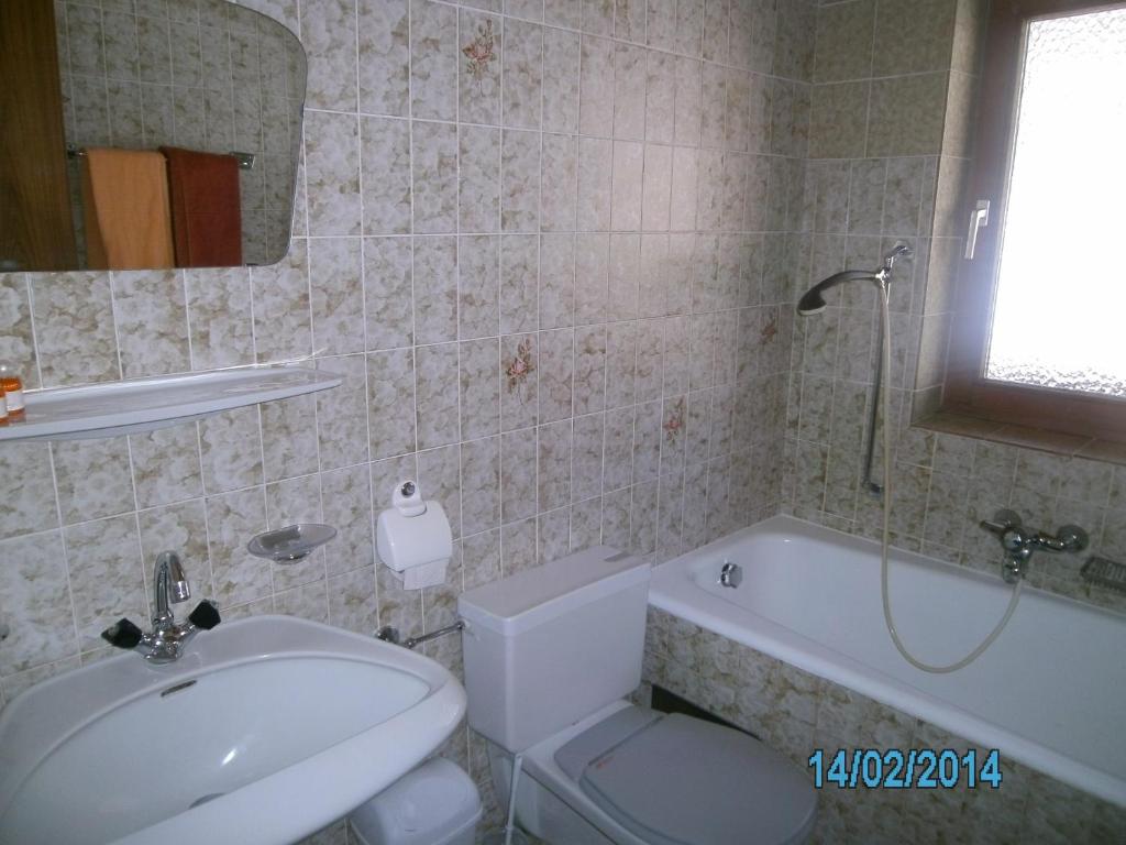 a bathroom with a sink and a toilet and a tub at Gästehaus Hirschenhof in Sölden