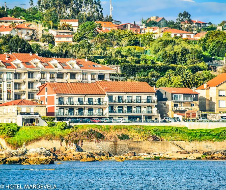 a group of buildings on a hill next to the water at Hotel Mardevela in Sanxenxo