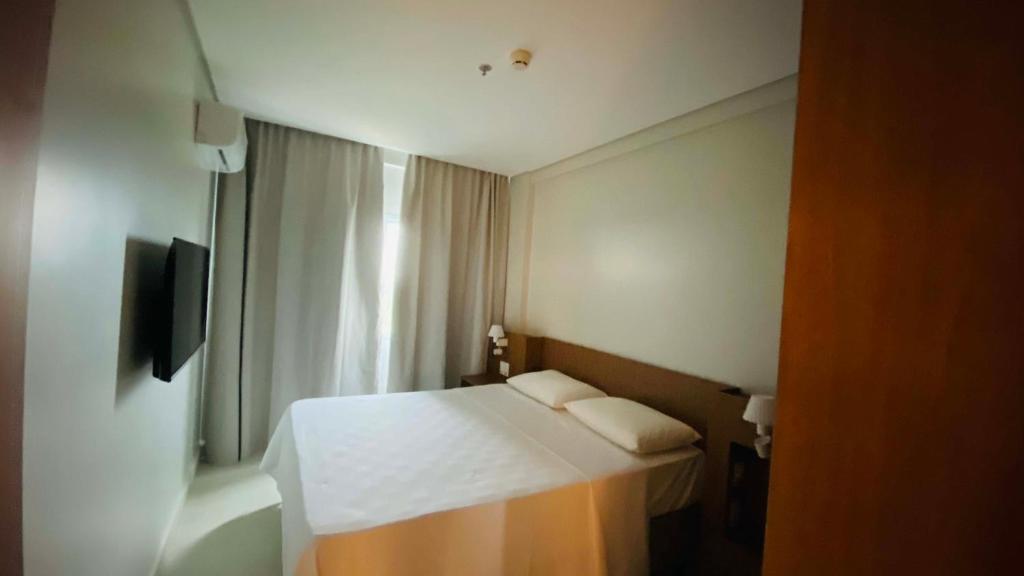 Un pequeño dormitorio con una cama blanca y una ventana en Salinas Exclusive Resort en Salinópolis