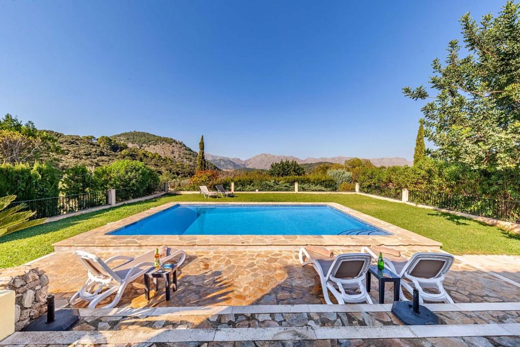 een zwembad met vier stoelen en een zwembad bij Villa Mala Garbo in Pollença