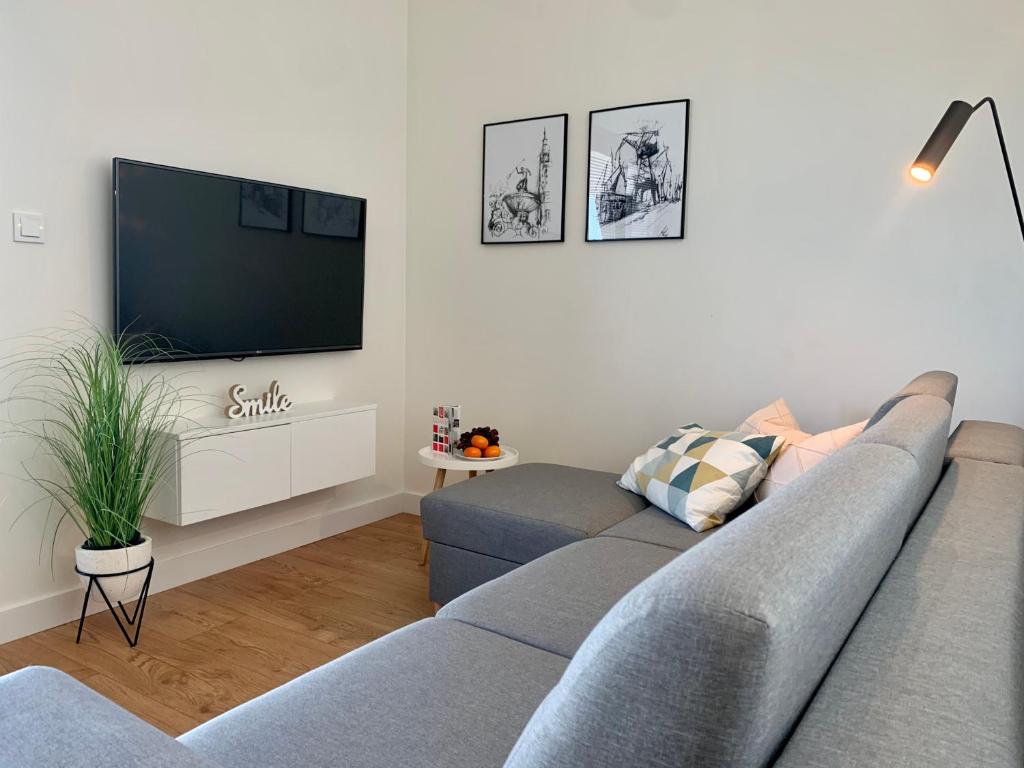 a living room with a couch and a flat screen tv at AURA Gdansk by Q4Apartments in Gdańsk