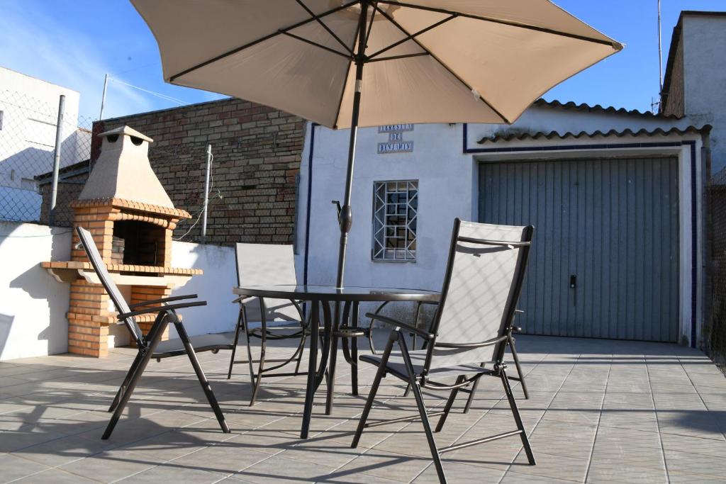 una mesa y sillas con una sombrilla en el patio en Casa Teresita, en Deltebre