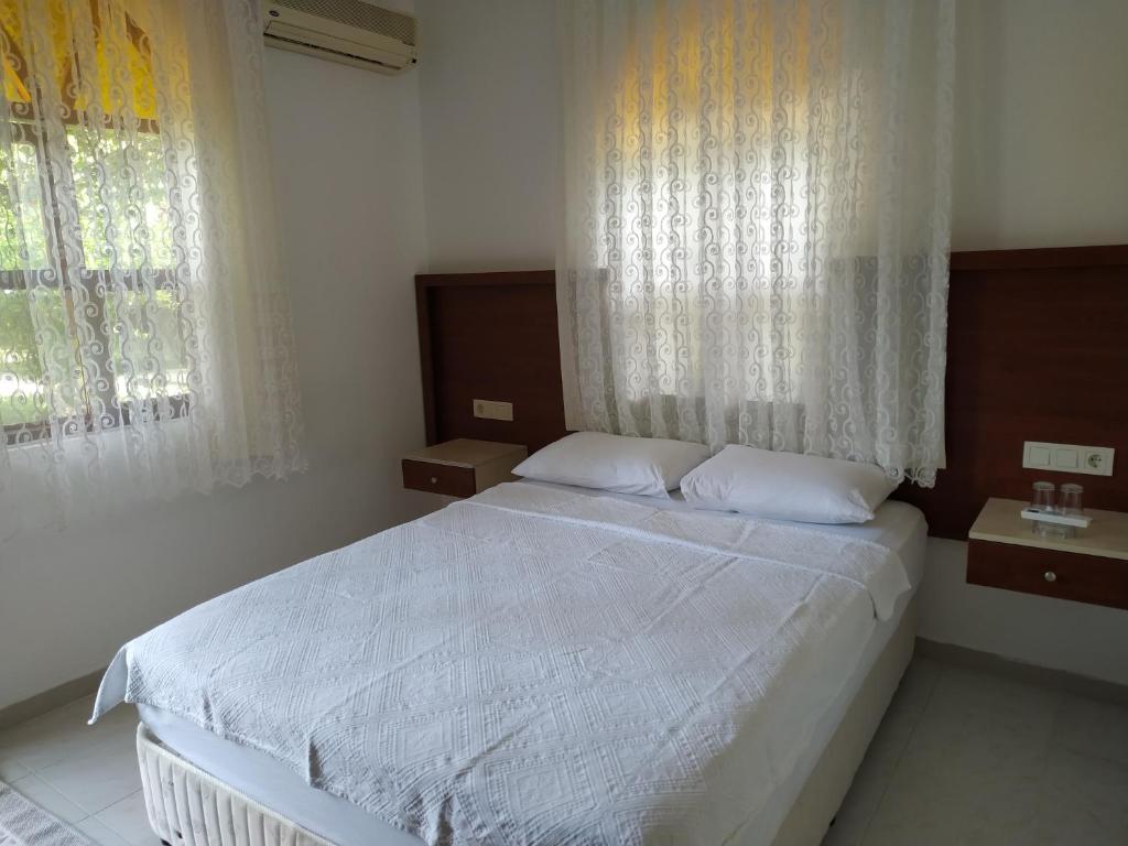 a bedroom with a white bed and two windows at Olympos Yavuz Hotel in Cıralı