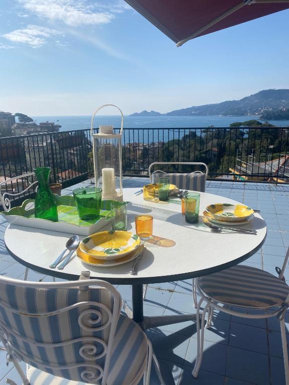 una mesa con platos y vasos en el balcón en Grande Attico con Vista Vicino al Centro by PortofinoVacanze, en Rapallo