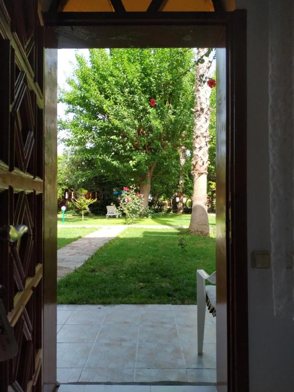 an open door to a yard with a tree at Olympos Yavuz Hotel in Cıralı
