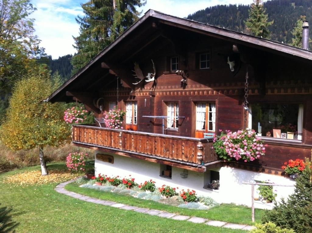 una casa en las montañas con flores en el balcón en Chalet Nyati, en Gstaad