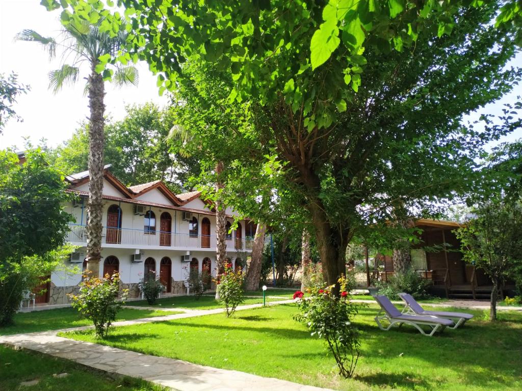 a large house with a lawn and trees at Olympos Yavuz Hotel in Cıralı