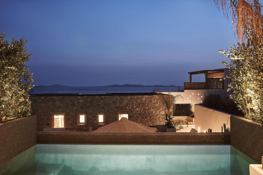 a large swimming pool with a view of the ocean at Habitat Mykonos All Suite Hotel in Agios Stefanos