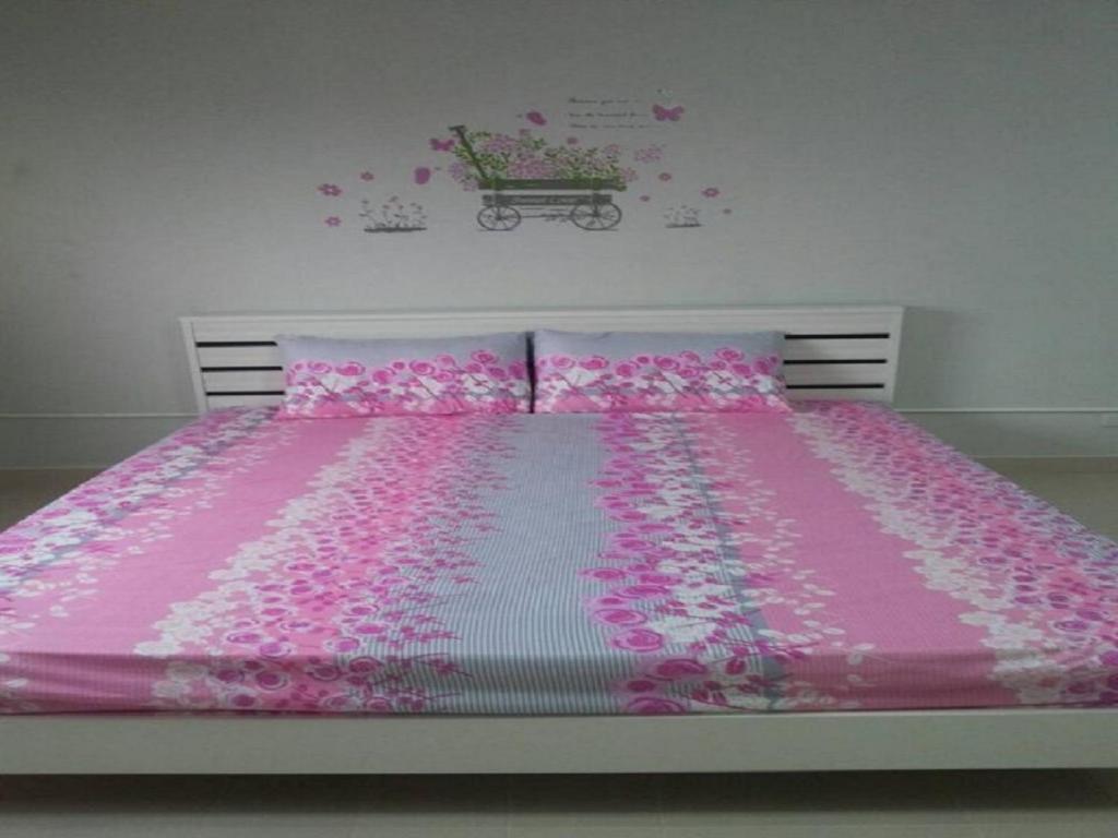 a bed with a pink bedspread and pink flowers on it at T8 Guest House Don Mueang Challenger in Ban Song Hong