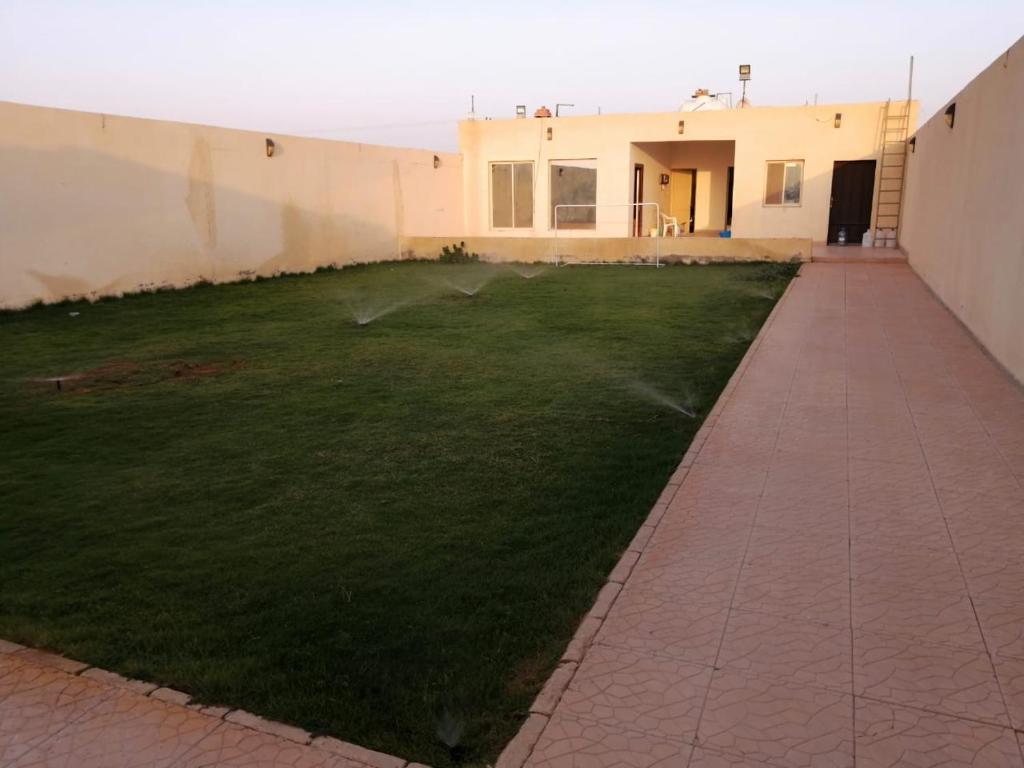 a grassy yard with a building and a sidewalk at استراحة الخير in Şulbūkh