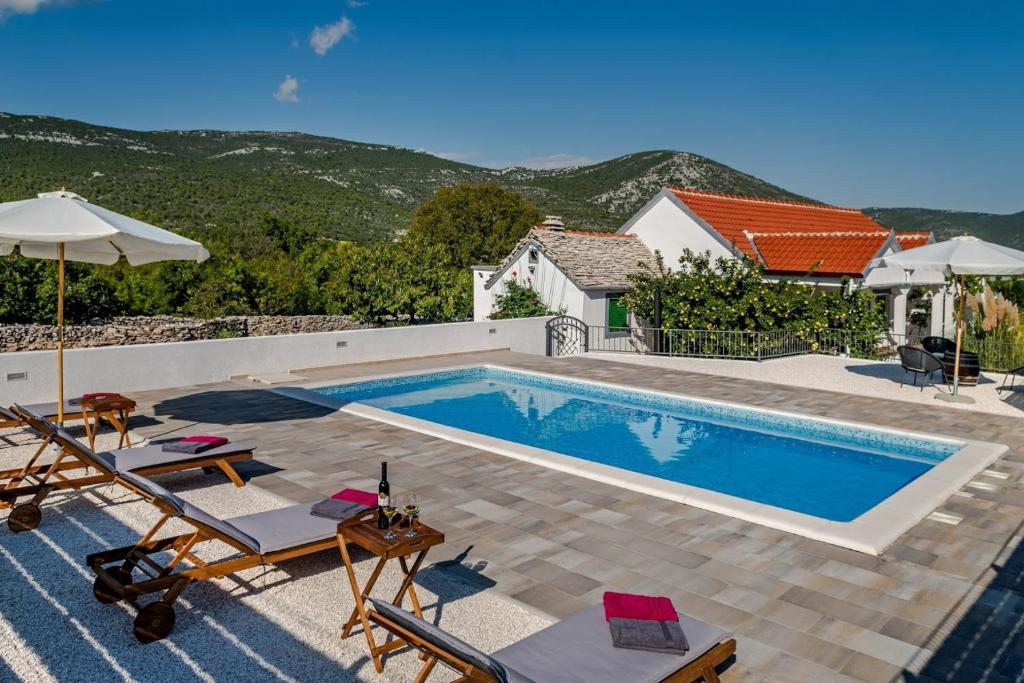 einen Pool mit zwei Stühlen und ein Haus in der Unterkunft House Camellia with fenced pool and playground in Blizna Donja