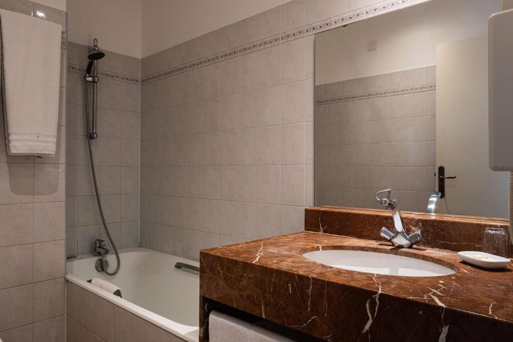 a bathroom with a sink and a bath tub at Best Western L&#39;Orangerie in Nîmes