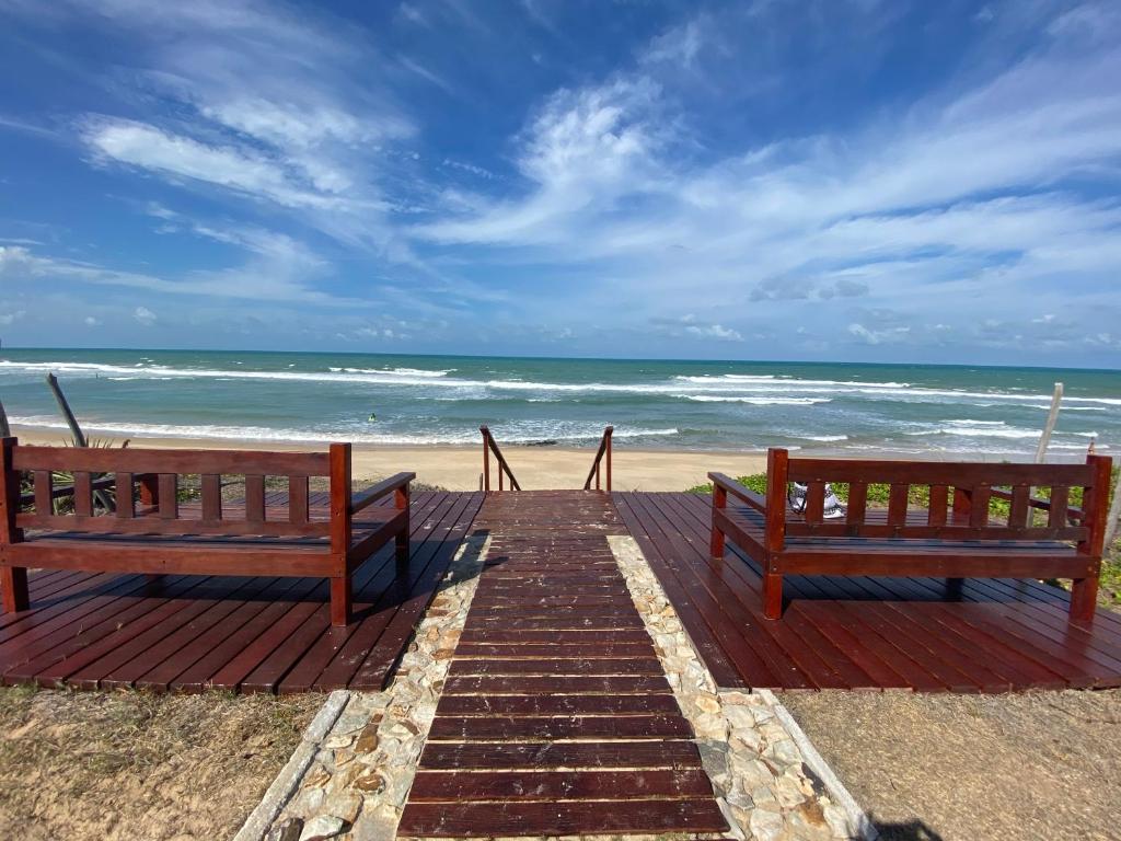 zwei Bänke auf einem hölzernen Gehweg zum Strand in der Unterkunft Taiba Beach Resort 01 Apto 2 quartos in São Gonçalo do Amarante