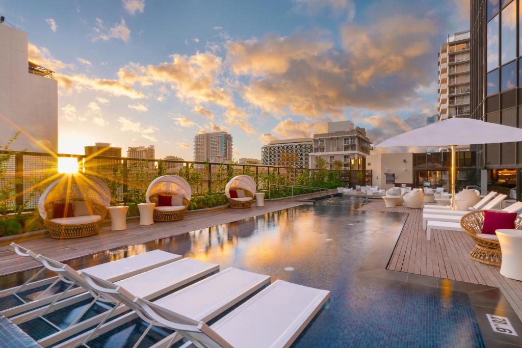 a pool on the rooftop of a building with lounge chairs at Hyatt Centric Waikiki Beach in Honolulu