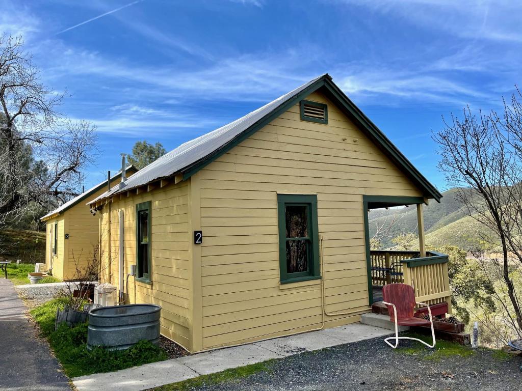 a yellow house with a red chair in front of it at Priest Station Cafe & Cabins in Groveland