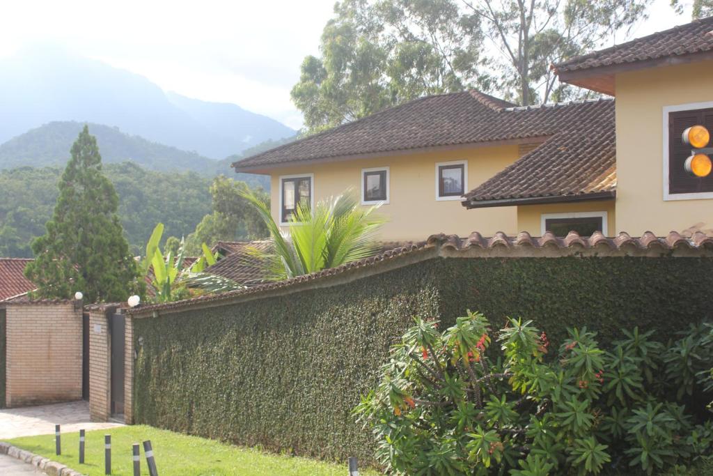 une maison avec une haie verte en face d'un bâtiment dans l'établissement Bendito Recanto, à Penedo