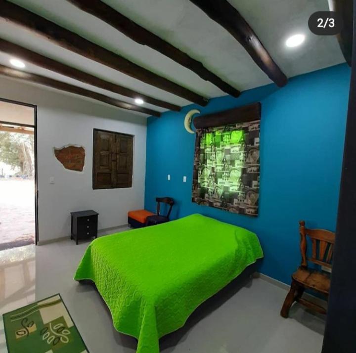 Un dormitorio con una cama verde y una pared azul en GhuRu Hotel Campestre en Firavitoba