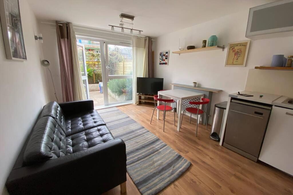ein Wohnzimmer mit einem Sofa und eine Küche mit einem Tisch in der Unterkunft Two Bedroom Garden Flat in Zone 2 London in London