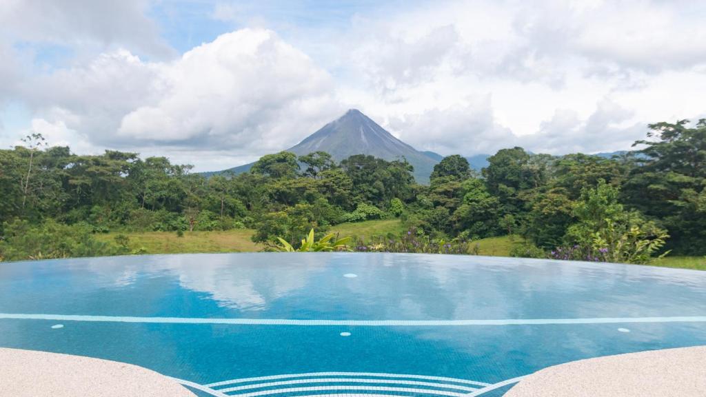 una piscina con una montagna sullo sfondo di Hotel Arenal Lodge a Fortuna