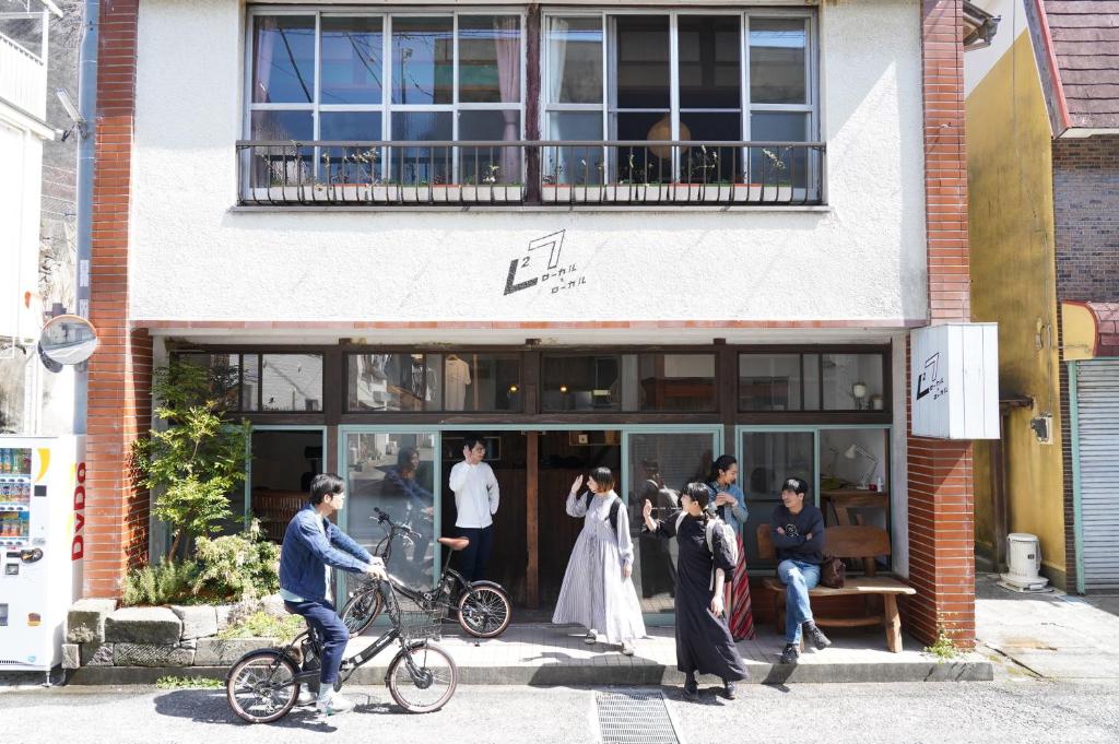 een groep mensen die buiten een gebouw staan bij ローカル×ローカル in Minamiizu