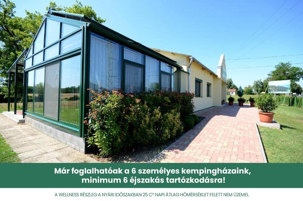 a house with large glass windows and a sidewalk at Szárszó Panzió in Balatonszárszó