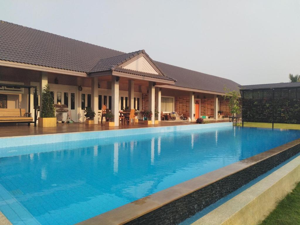 uma piscina em frente a uma casa em Coconut Garden Retreat em Samut Songkhram