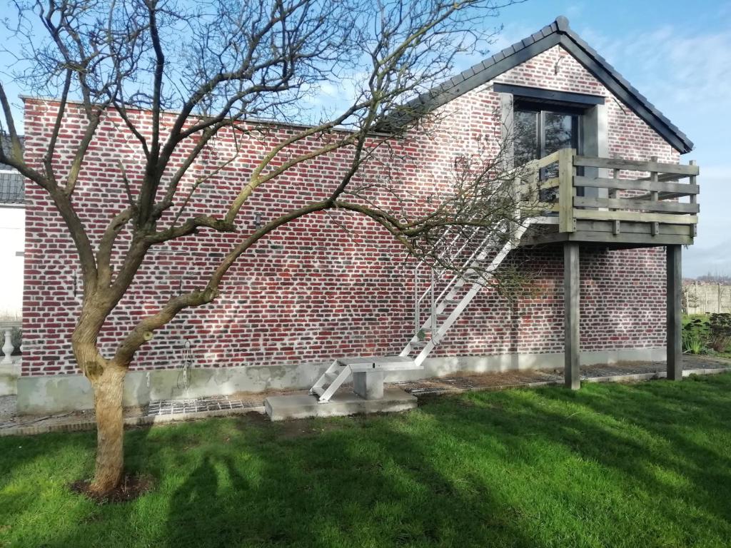 ein Backsteingebäude mit einer Leiter neben einem Baum in der Unterkunft Etage à la ferme avec piscine intérieure privative, selon date in La Bassée