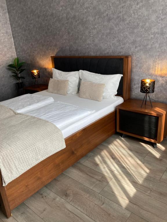 um quarto com uma grande cama de madeira e 2 candeeiros em SOLE Apartment 1 em Satu Mare