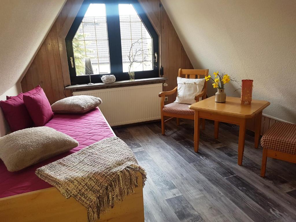 um quarto no sótão com uma cama, uma mesa e uma janela em Montanregion Erzgebirge-Ihr Urlaub ist unsere Herzenssache em Langenberg