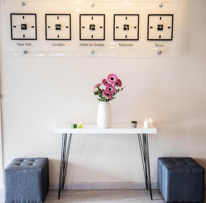 une table avec un vase de fleurs et des photos sur le mur dans l'établissement Le Grazie Hotel, à Assise